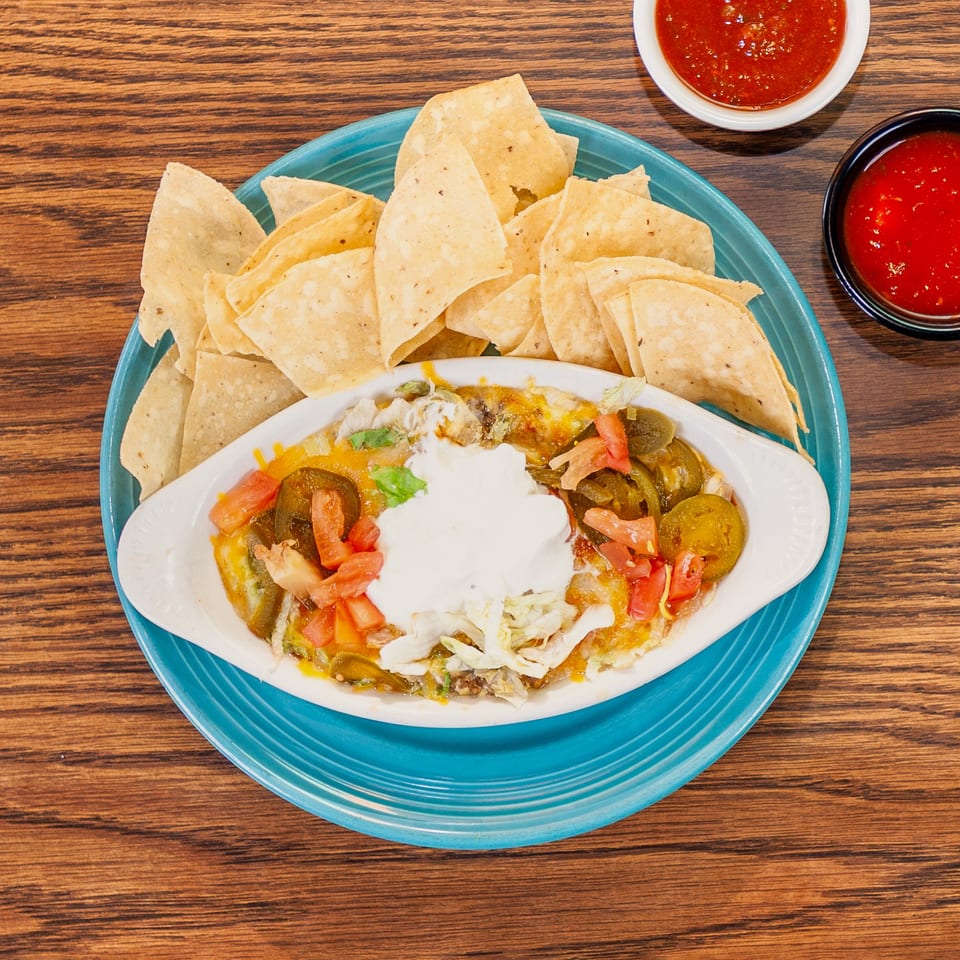 Queso dip with jalapeños, tomatoes, and sour cream, served with tortilla chips and salsa.